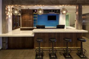 um bar com bancos num quarto com televisão em Moxy Santa Barbara em Santa Bárbara