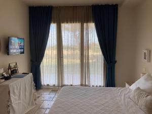 a bedroom with a large window with blue curtains at The Bee House in San Giovanni
