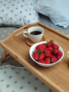 a tray with a bowl of strawberries and a cup of coffee at Apartman NS Dan FREE PARKING in Novi Sad