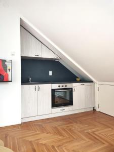 an attic kitchen with white cabinets and a microwave at Apartman NS Dan FREE PARKING in Novi Sad