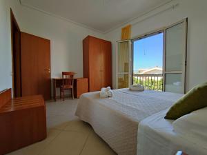 a bedroom with a bed and a large window at Appartamenti in Villa Polimnia in Fontane Bianche