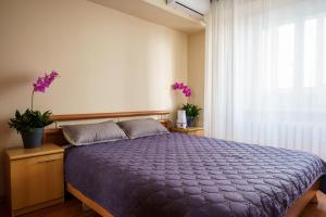 a bedroom with a bed with a purple comforter and a window at Золотой квадрат 60 кв2 in Almaty