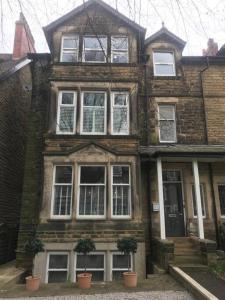 an old brick house with potted plants in front of it at Dragon Parade Apartment in Harrogate