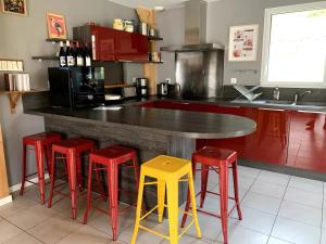 a kitchen with a counter with four red and yellow stools at Chalet Las Abelhas in Le Mont-Dore