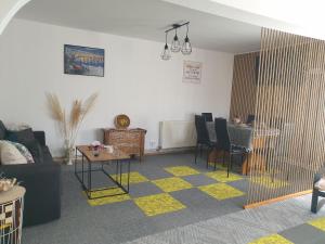 ein Wohnzimmer mit einem Sofa, einem Tisch und Stühlen in der Unterkunft Casuta din Gradina in Horezu