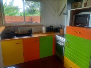 una cucina con armadi colorati, un lavandino e una finestra di Bungalow de charme a Capesterre-Belle-Eau