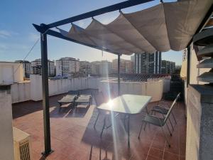 patio con tavolo, sedie e ombrellone di BEAUTIFUL PENTHOUSE SOLARIUM IN BOLICHES BEACH a Fuengirola
