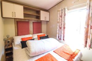 1 dormitorio con cama con almohadas y ventana en Brilliant 8 Berth Caravan Near Walton-on-the-naze In Essex - 17023nm, en Walton-on-the-Naze