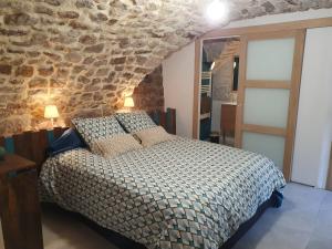 1 dormitorio con cama y pared de piedra en La Storya, en Meyras