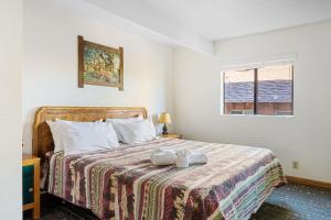 a bedroom with a bed with a blanket and a window at 02- American Black Bear At Village Suites Inn in Big Bear Lake