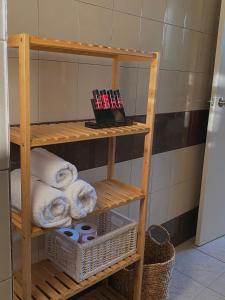estante de madera con toallas y cestas en el baño en Helen's cozy studio (close to the airport), en Koropíon