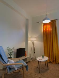 salon z krzesłem, stołem i telewizorem w obiekcie Helen's cozy studio (close to the airport) w mieście Koropi