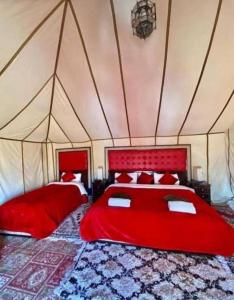 メルズーガにあるLuxury Desert Campのテント内の赤いベッド2台付きのベッドルーム1室