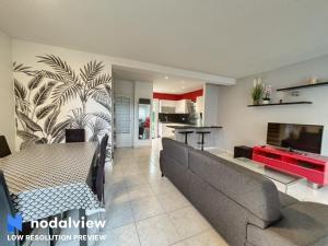 uma sala de estar com um sofá e uma televisão em Villa Azurella em Villeneuve-Loubet