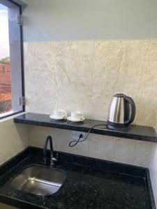 a kitchen counter with a sink and a tea kettle at España Suites Hotel in Ciudad del Este