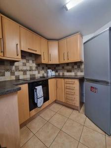 a kitchen with wooden cabinets and a white refrigerator at Maidstone castle 3bedroom free sports channels, parking in Kent