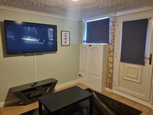 a living room with a tv and a table and a door at Maidstone castle 3bedroom free sports channels, parking in Kent