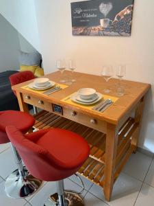 uma mesa de madeira com cadeiras vermelhas e copos de vinho em Diane‘s Ferienwohnung em Meckesheim