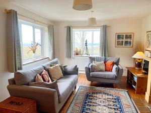 ein Wohnzimmer mit 2 Sofas und 2 Fenstern in der Unterkunft Yew Tree Cottage in Great Malvern
