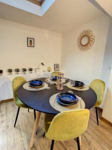 a dining room table with yellow chairs and a table with plates at Charmant triplex centre-ville de Chantilly in Chantilly