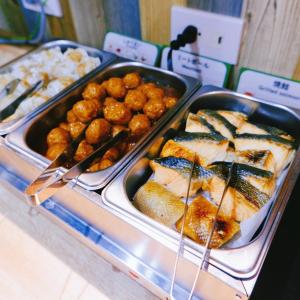 un buffet con diversi vassoi di cibo su un tavolo di Kamata Inn Social a Tokyo