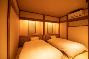 2 Betten in einem kleinen Zimmer mit Beleuchtung in der Unterkunft Kyufukujyuin Takei Ryokan in Nagano