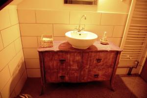a bathroom with a white sink on a wooden dresser at Magdi vendégház in Šupljak