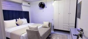 a bedroom with a large white bed and a chair at Beautiful One Bedroom Apartment in Opebi, Ikeja in Ikeja