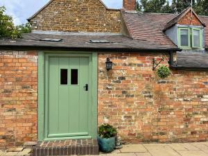 a green door on the side of a brick building at Friends, Family and Colleagues Suite in Napton on the Hill