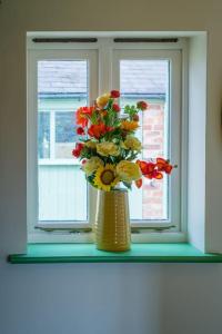 a vase with flowers sitting on a window sill at Friends, Family and Colleagues Suite in Napton on the Hill
