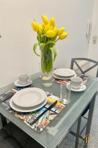 a table with plates and a vase of yellow flowers at UNLIMITED - schön & zentral wohnen perfekt für kurze Aufenthalte in Bamberg