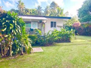 a small white house in a yard with trees at Avarua Escape, Rarotonga in Avarua