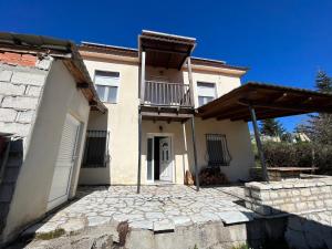Dieses weiße Haus verfügt über einen Balkon und eine Terrasse. in der Unterkunft Chalet Karpenisi in Karpenisi