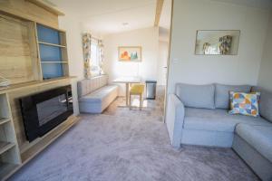 a living room with a couch and a fireplace at Lovely 6 Berth Caravan Close To The Beach In Suffolk Ref 68030bs in Lowestoft