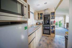 a kitchen with a refrigerator and a sink at Lovely 6 Berth Caravan Close To The Beach In Suffolk Ref 68030bs in Lowestoft