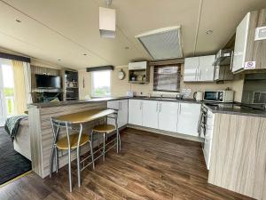 a kitchen with white cabinets and a table and chairs at Modern 6 Berth Caravan At Martello Beach In Essex Ref 29002sv in Clacton-on-Sea