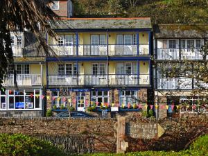 a building with balconies and a car parked in front of it at Riverside Cottage B&B in Lynmouth