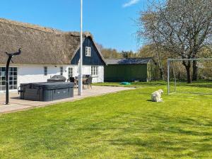 a dog sitting in the grass in front of a house at 6 person holiday home in Gedser in Gedser