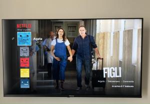 a television screen with a picture of a man and a woman at Bed-da Catania Rooms in Catania