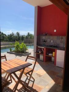 eine Terrasse mit einem Tisch und Stühlen sowie eine Küche in der Unterkunft Vila Kite Lagoon in Parajuru