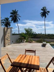 einen Holztisch und Stühle auf einer Terrasse mit Palmen in der Unterkunft Vila Kite Lagoon in Parajuru