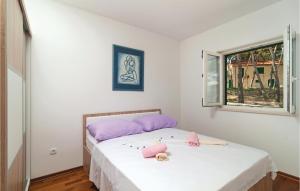 1 Schlafzimmer mit 2 Betten mit rosa Kissen und einem Fenster in der Unterkunft Pet Friendly Apartment In Sutivan With House Sea View in Sutivan