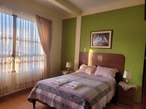 Un dormitorio con una cama con paredes verdes y una ventana en Hostal Kurmi - Coroico, en Coroico