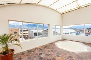 Habitación blanca grande con bañera y ventanas en HOSTAL DEL RÍO, en Ibarra