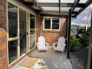 two white chairs sitting on a patio next to a building at Guesthouse in Papamoa Beach in Papamoa