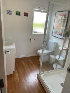 a bathroom with a toilet and a glass shower at Guesthouse in Papamoa Beach in Papamoa