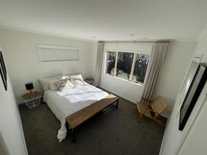 a small bedroom with a bed and a window at Guesthouse in Papamoa Beach in Papamoa