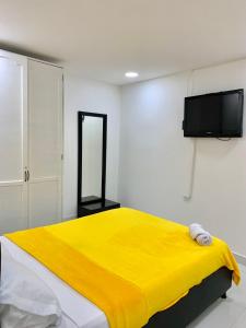 1 dormitorio con cama amarilla y TV de pantalla plana en Casa Nómada - To work and enjoy!, en Santa Marta
