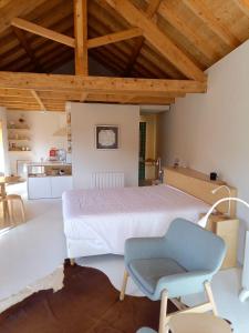 a bedroom with a white bed and a blue chair at Armazém de Sal - Alojamento Loft in Rio Maior