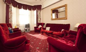 a living room with red furniture and a mirror at Denewood Hotel in Bournemouth